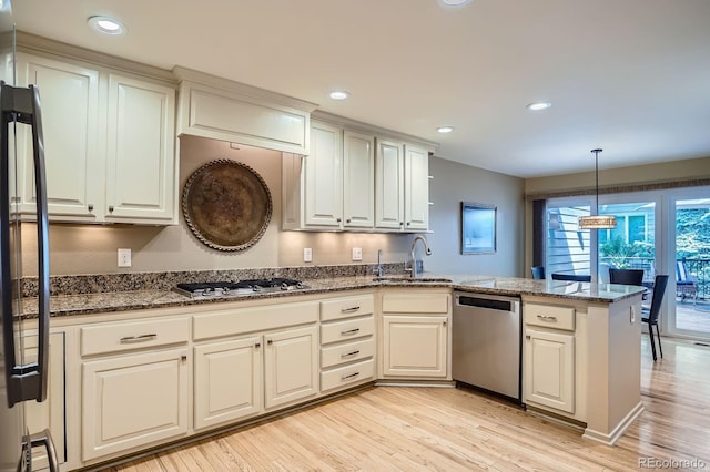 8505 E Temple Dr Unit 473, Denver, CO 80237 - kitchen with stainless steel appliances, a peninsula, light wood-style floors, pendant lighting, and dark stone countertops