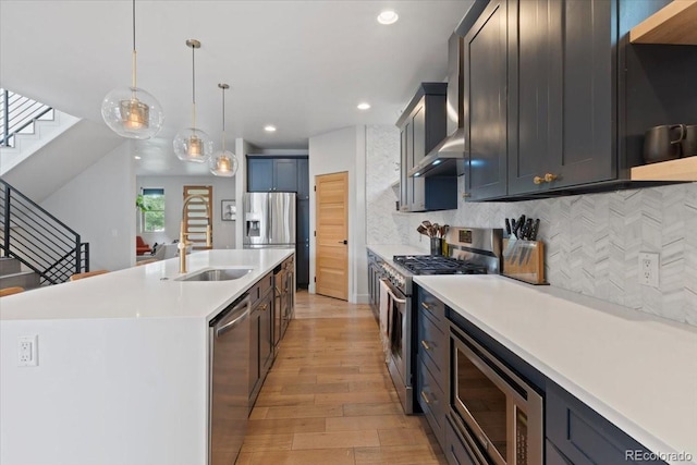 2533 N Emerson St, Denver, CO 80205 - kitchen with appliances with stainless steel finishes, a sink, light wood-style flooring, a center island with sink, and light countertops