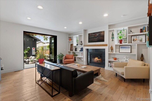 2533 N Emerson St, Denver, CO 80205 - living area featuring a glass covered fireplace, light wood-type flooring, recessed lighting, built in shelves, and baseboards