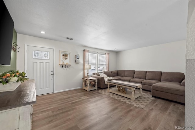 living area featuring visible vents, baseboards, and wood finished floors