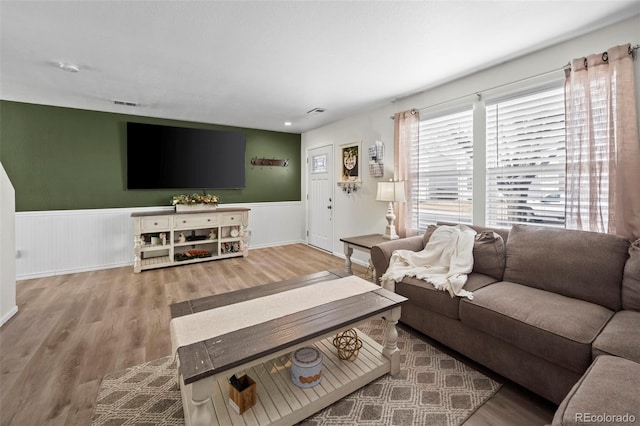 living room with visible vents, wood finished floors, and wainscoting