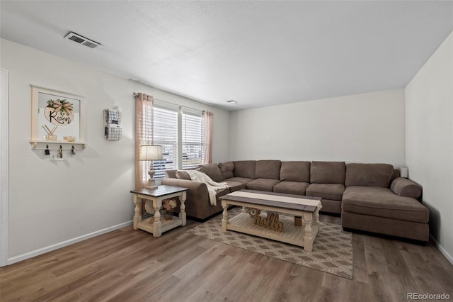 living room featuring visible vents, baseboards, and wood finished floors