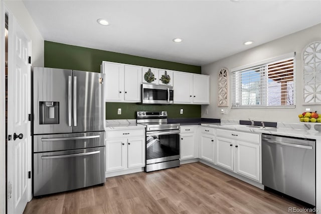 kitchen with white cabinets, light stone countertops, light wood-style floors, and appliances with stainless steel finishes