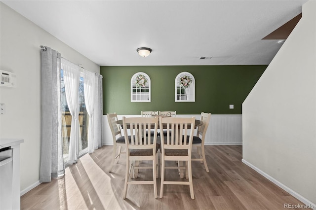 dining room with a wainscoted wall, visible vents, and light wood-type flooring