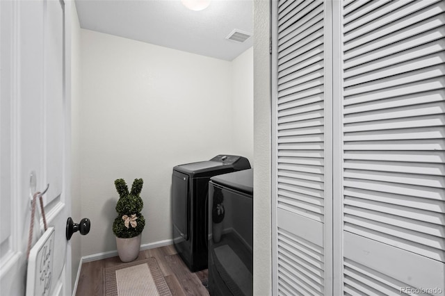 clothes washing area with visible vents, baseboards, laundry area, wood finished floors, and separate washer and dryer