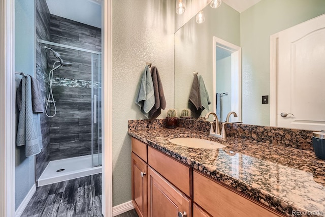 11839 E Fair Ave, Greenwood Village, CO 80111 - bathroom with vanity, a stall shower, wood finished floors, and a textured wall