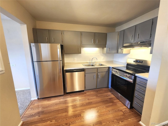 kitchen with gray cabinets, a sink, light countertops, appliances with stainless steel finishes, and under cabinet range hood