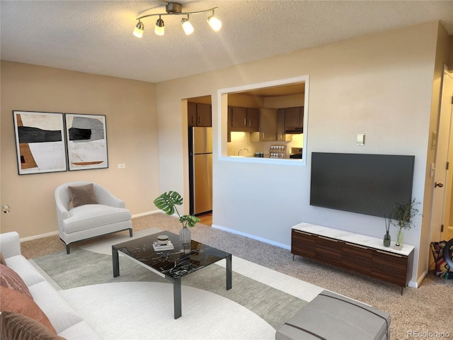 living area with light carpet, a textured ceiling, and baseboards