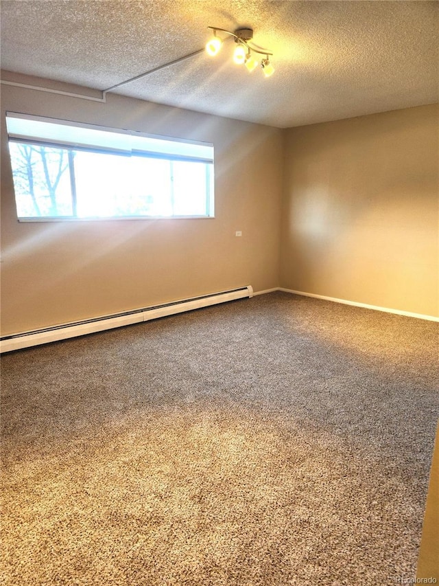 spare room featuring a baseboard heating unit, carpet floors, a textured ceiling, and baseboards