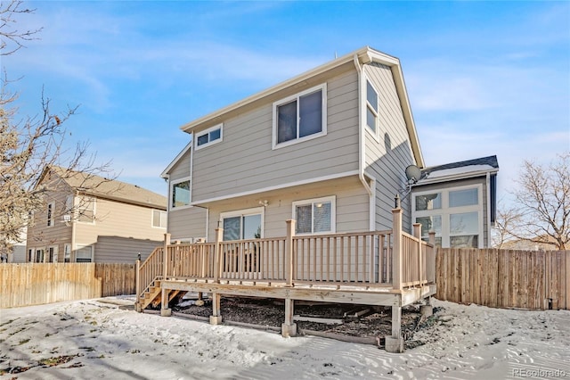 snow covered back of property with a wooden deck