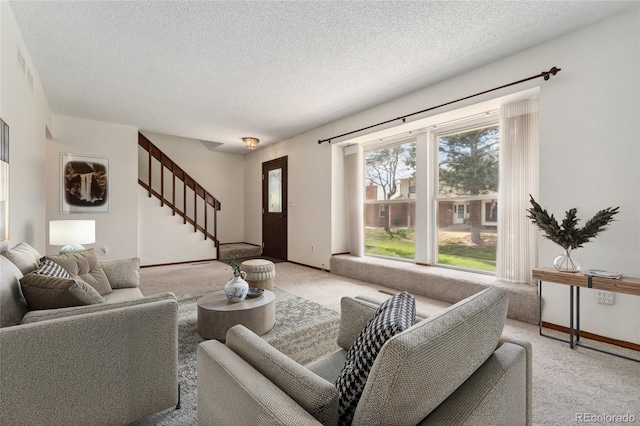 living area with baseboards, stairs, a textured ceiling, and light colored carpet