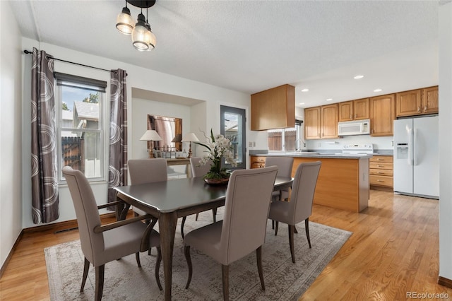 dining space with recessed lighting, a textured ceiling, and light wood-style flooring