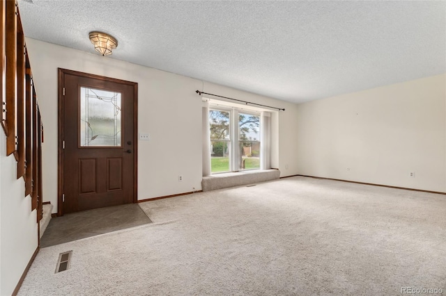 carpeted entrance foyer featuring stairway, baseboards, a textured ceiling, and visible vents
