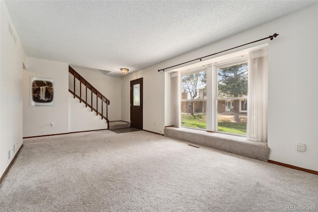 interior space with carpet floors, a textured ceiling, baseboards, and stairs