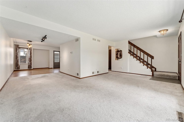 unfurnished living room featuring visible vents, carpet flooring, stairs, and baseboards