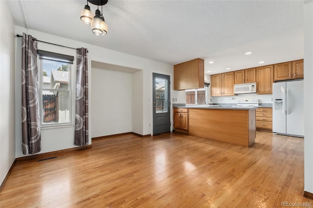 kitchen with a sink, baseboards, a peninsula, white appliances, and light wood-style flooring