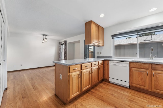 kitchen featuring white dishwasher, a sink, brown cabinets, and light wood-style flooring