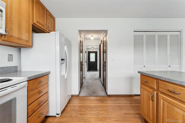 kitchen with brown cabinetry, white appliances, and light wood-style flooring