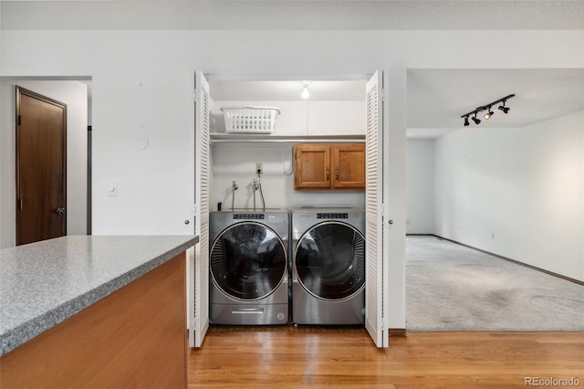 clothes washing area with separate washer and dryer, rail lighting, cabinet space, and light wood-style floors