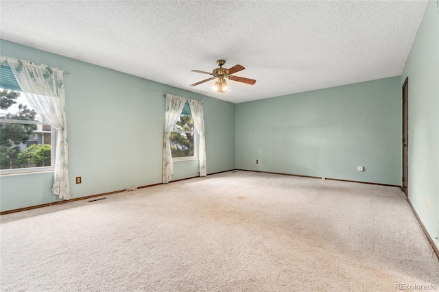 empty room featuring carpet floors, visible vents, baseboards, ceiling fan, and a textured ceiling