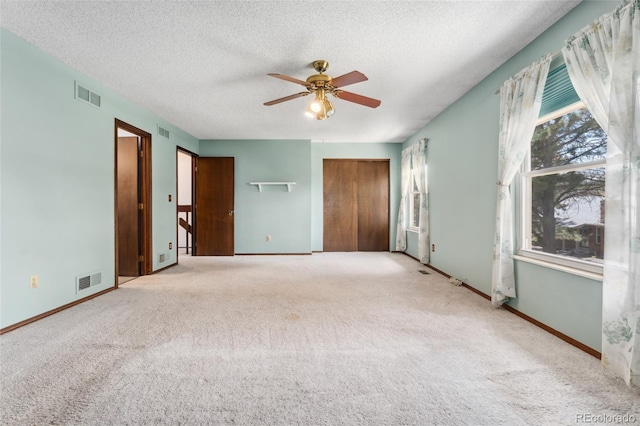 unfurnished bedroom featuring carpet flooring, a textured ceiling, and visible vents
