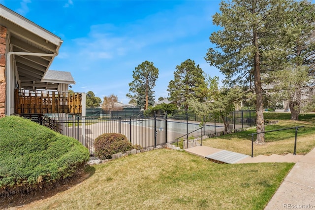 view of tennis court featuring a lawn and fence