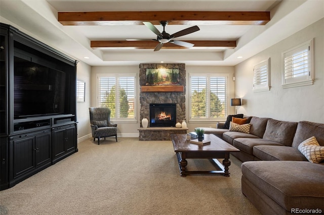 carpeted living room featuring a stone fireplace, beam ceiling, and ceiling fan