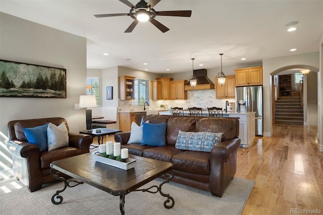 living room with light wood-type flooring, sink, and ceiling fan