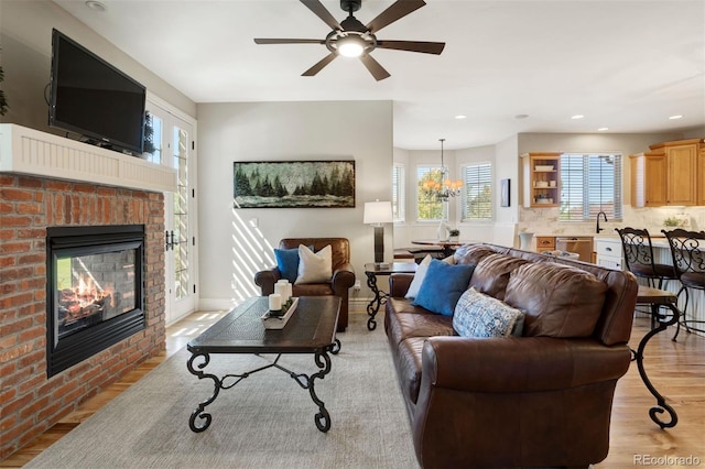 living room with ceiling fan, a fireplace, and light hardwood / wood-style flooring