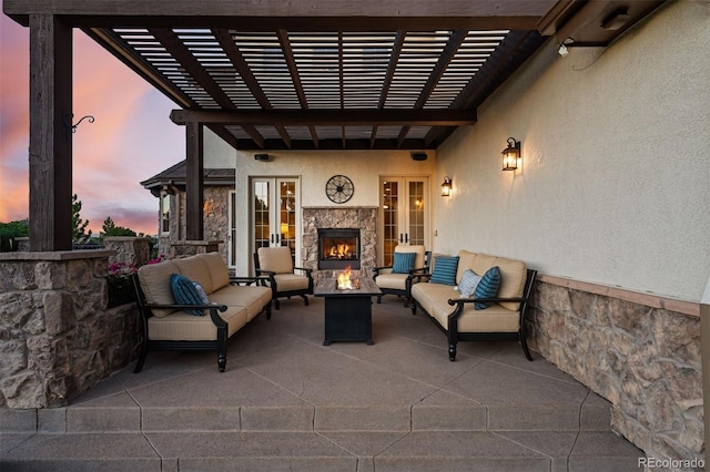 patio terrace at dusk featuring an outdoor living space with a fireplace, a pergola, and french doors