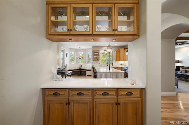 kitchen featuring light hardwood / wood-style floors, high end stove, pendant lighting, sink, and a notable chandelier