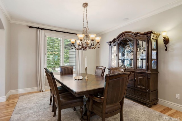 dining room featuring a chandelier, light hardwood / wood-style floors, and crown molding