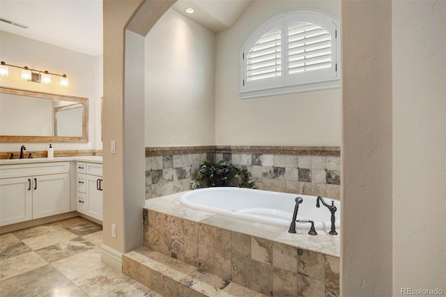 bathroom featuring tiled tub and vanity