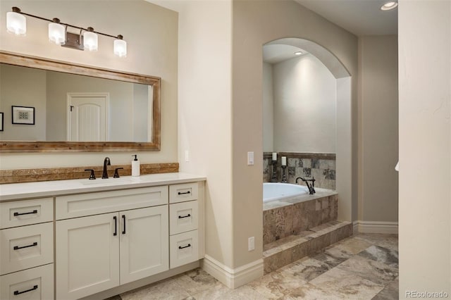 bathroom featuring a relaxing tiled tub and vanity