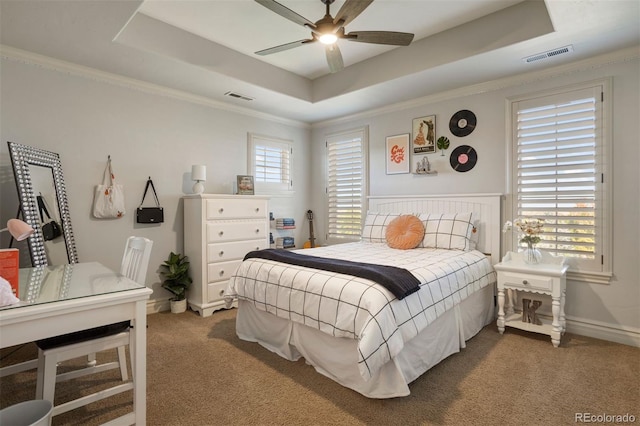 carpeted bedroom with ornamental molding, multiple windows, a raised ceiling, and ceiling fan