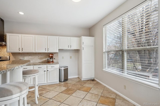 kitchen featuring decorative backsplash, white cabinetry, and light stone countertops