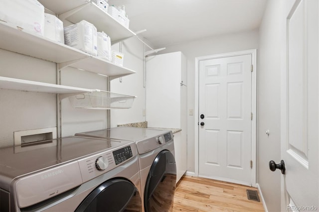 clothes washing area with separate washer and dryer and light hardwood / wood-style floors