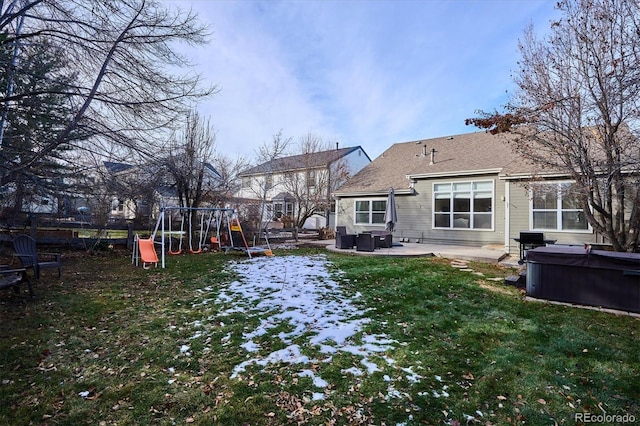 back of property with a playground, a yard, a patio, and a hot tub