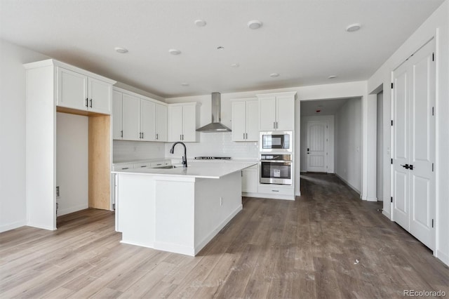 25283 E Warren Pl, Aurora, CO 80018 - kitchen with stainless steel appliances, wall chimney exhaust hood, a sink, wood finished floors, and decorative backsplash