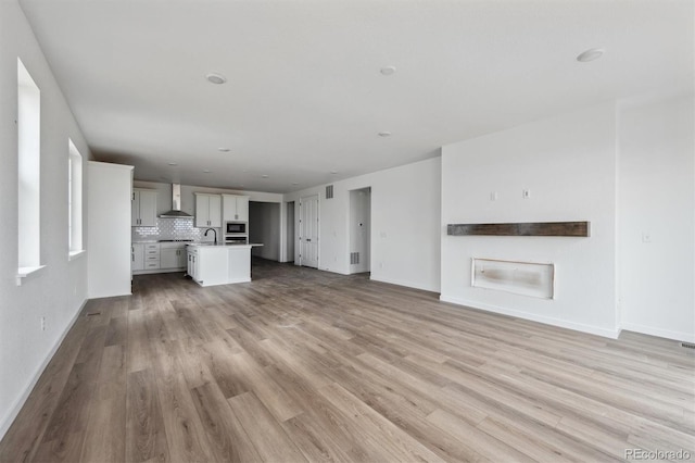 25283 E Warren Pl, Aurora, CO 80018 - unfurnished living room featuring a sink, light wood finished floors, and baseboards