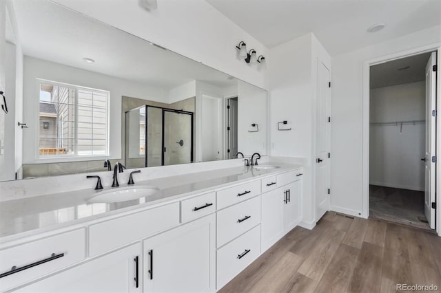 25283 E Warren Pl, Aurora, CO 80018 - full bathroom with a shower stall, double vanity, wood finished floors, and a spacious closet