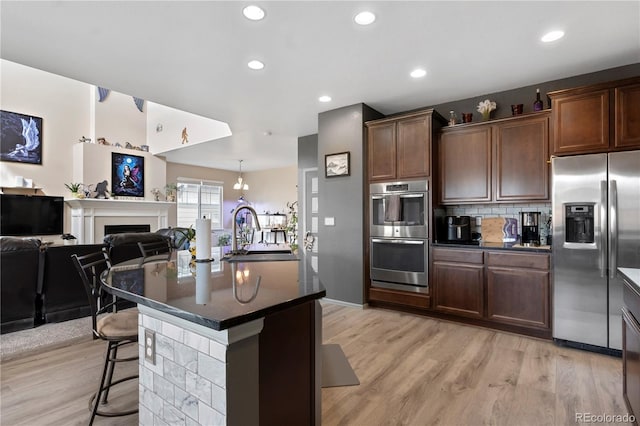 kitchen featuring sink, light hardwood / wood-style floors, a breakfast bar area, a kitchen island with sink, and appliances with stainless steel finishes