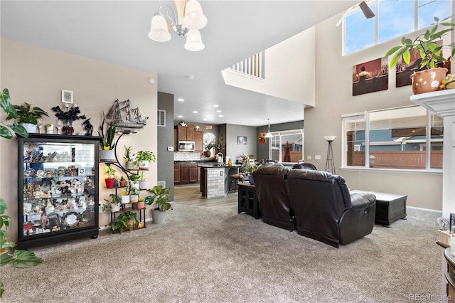 carpeted living room with ceiling fan with notable chandelier and a wealth of natural light