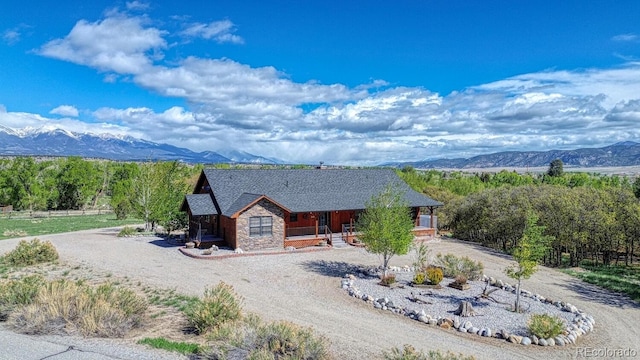 8126 Buck Run, Salida, CO 81201 - view of front of home featuring dirt driveway, a mountain view, stone siding, and covered porch