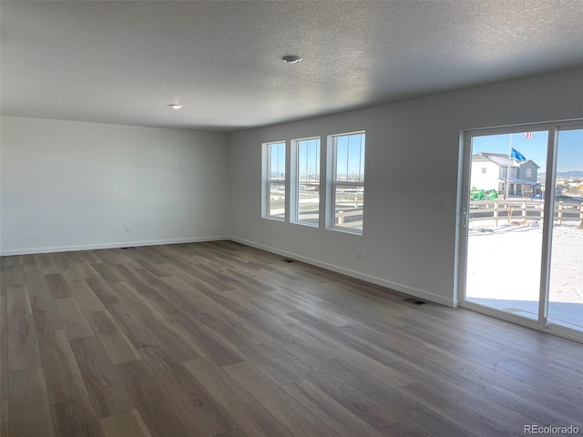 spare room featuring hardwood / wood-style floors and a textured ceiling