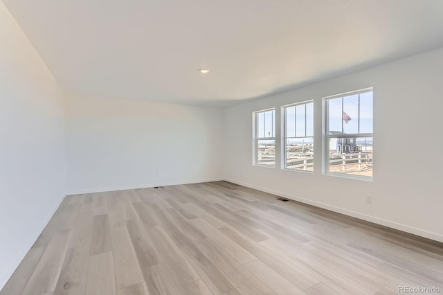 unfurnished room with recessed lighting, light wood-type flooring, baseboards, and visible vents