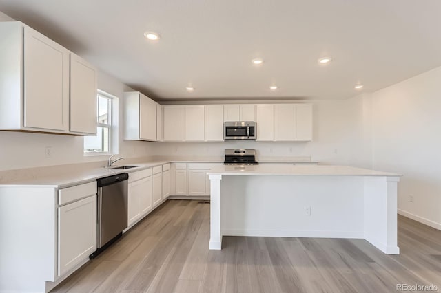 kitchen featuring white cabinets, appliances with stainless steel finishes, light wood-type flooring, and light countertops