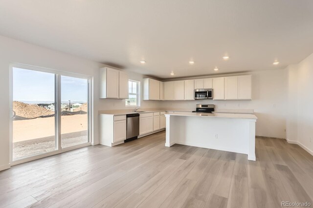 3909 N Shawnee St, Aurora, CO 80019 - kitchen with light wood-style flooring, white cabinetry, recessed lighting, appliances with stainless steel finishes, and light countertops