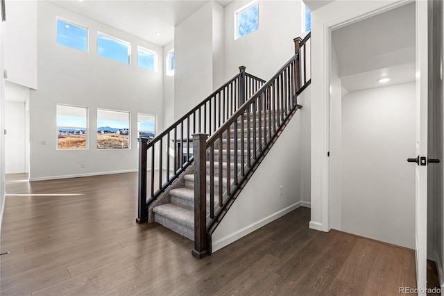 stairs with hardwood / wood-style flooring and a towering ceiling