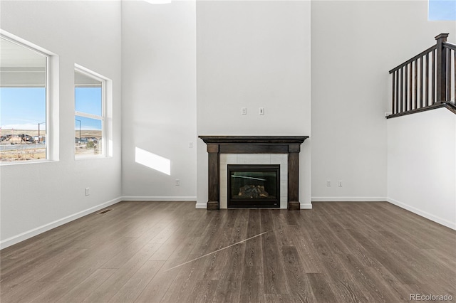 unfurnished living room with dark hardwood / wood-style floors and a tile fireplace